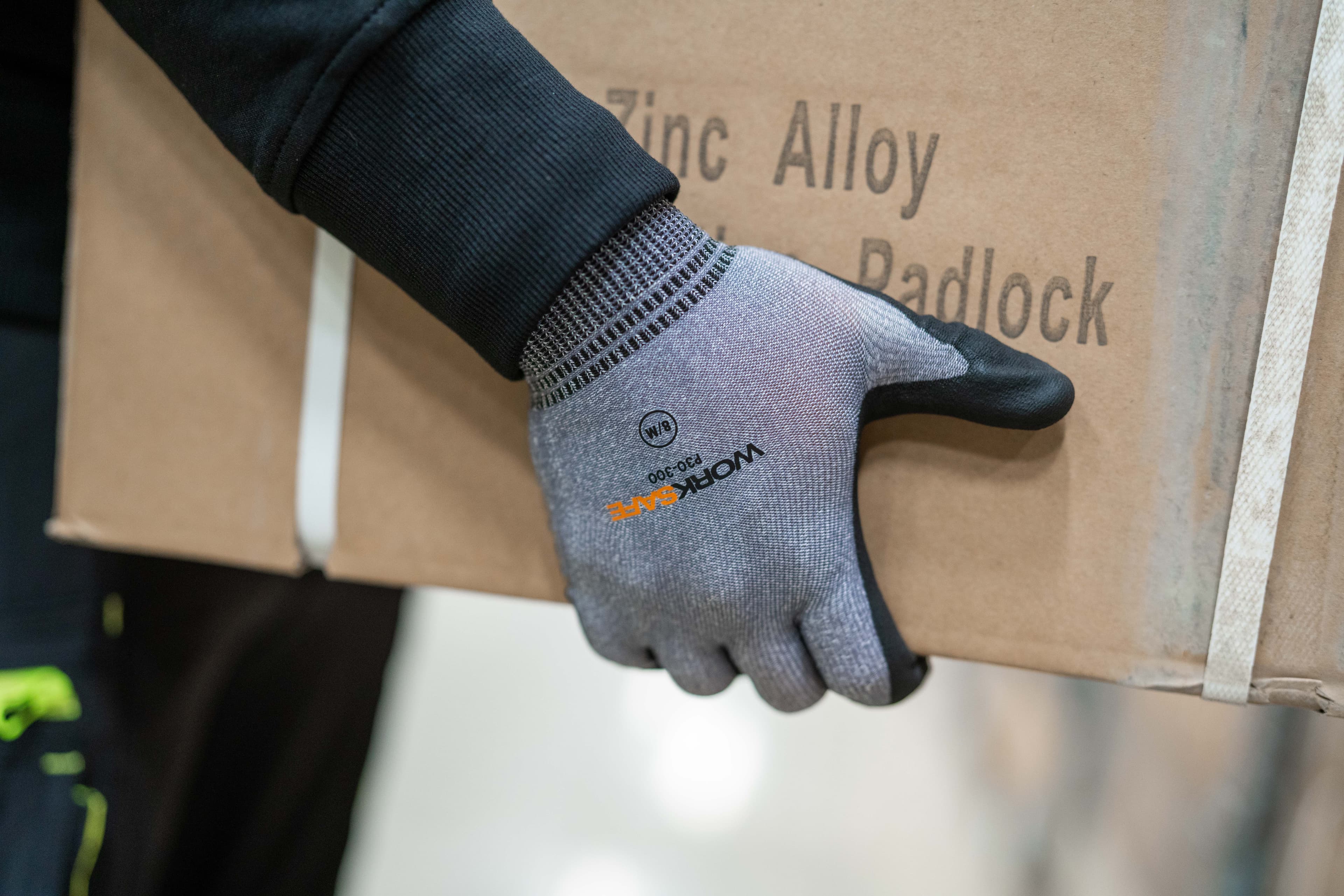 Närbild på hand och handske från Worksafe som bär en låda