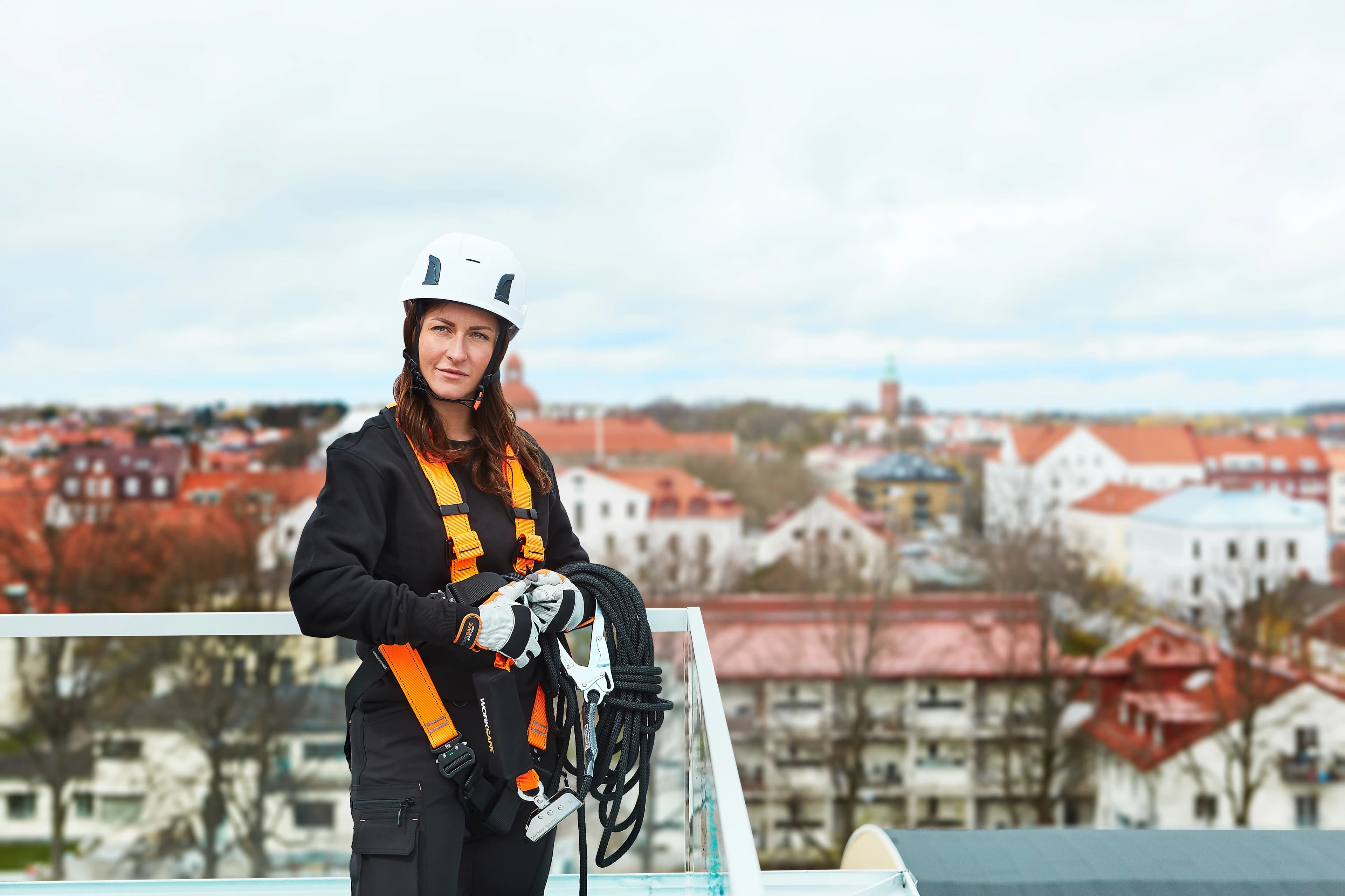 En kvinna i Worksafe fallskydd uppe på hustak